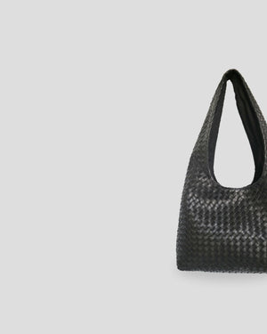 Close-up view of woven leather texture on women's shoulder bag showing detailed braided pattern and craftsmanship