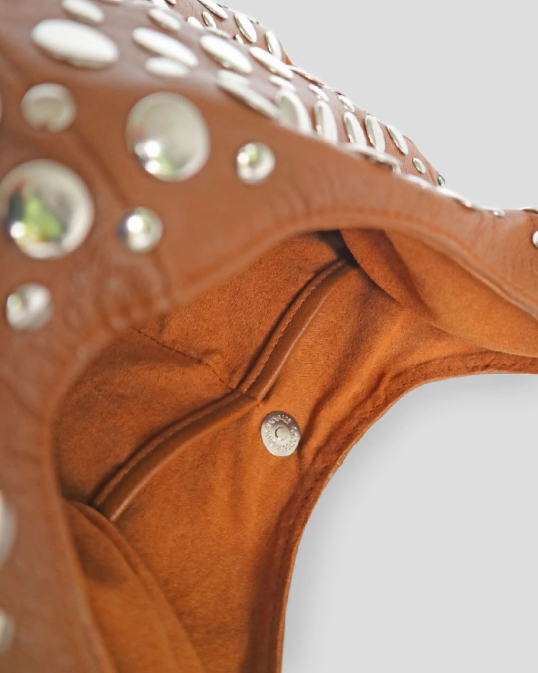 Close-up of a brown leather bag with silver studs an showing the pocket