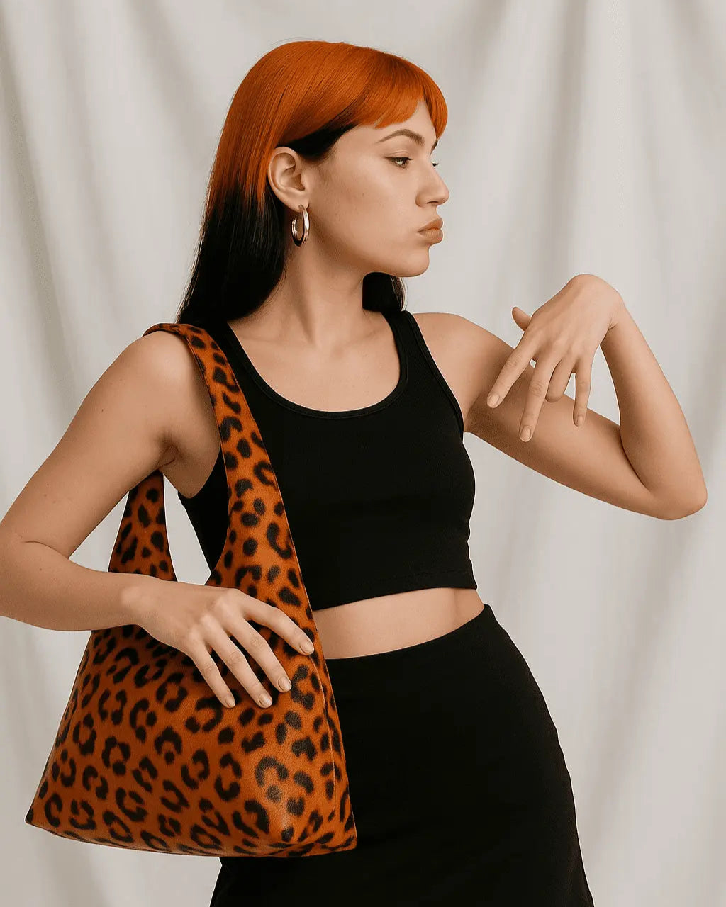 Woman holding a leopard print bag against a plain studio background 